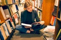 Student girl sitting on the floor and reading a book in the library Royalty Free Stock Photo