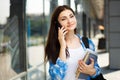 Student girl talking on mobile phone standing near college build Royalty Free Stock Photo