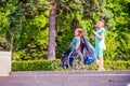 A student girl walks with her friend to the disabled sitting in a wheelchair along the Volga River embankment on a sunny summer da