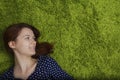 Woman smiles feeling happy lying down on green artificial grass Royalty Free Stock Photo