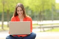 Student girl working with a laptop in a green park