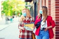 Student girls are exploring new city together. Summer vacation during coronavirus pandemic. Tourists in medical masked Royalty Free Stock Photo