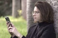 Student guy in glasses and business clothes,holding a cell phone of the Apple iPhone 14 PRO MAX brand,dialing a number,looking at Royalty Free Stock Photo