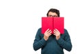 Student guy hiding behind a red book, looking suspicious aside isolated on white background with copy space. Scared nerd person, Royalty Free Stock Photo