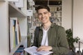 Student guy look at camera posing in library with textbook Royalty Free Stock Photo
