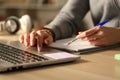 Student hands comparing laptop content and notes at night Royalty Free Stock Photo