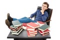 Student having a rest with the legs on the desk, daydreaming among piles of books Royalty Free Stock Photo