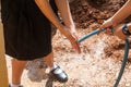 Student holding garden hose spraying fresh water to wash hands