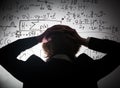 Student holding his head looking at complex math formulas on whiteboard. Problem to solve Royalty Free Stock Photo