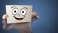 Student holding a paper with laughing emoticon in front of his face