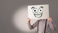 Student holding a paper with laughing emoticon in front of his face