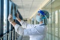 Student intern in a protective suit and face shield looks at a xray film of the lungs, covid19