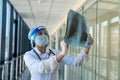 Student intern in a protective suit and face shield looks at a xray film of the lungs, covid19