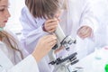 Student learning chemistry. Positive joyful smart boy and girl tesing and using a microscope in science class. Two children help