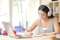 Student learning with headphones taking notes Royalty Free Stock Photo