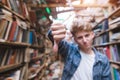 Student in the library shows a finger down. Dislike library and books Royalty Free Stock Photo