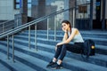 Student life, exams, sessions. Schoolgirl with a backpack sitting on the steps of the institution