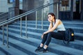 Student life, exams, sessions. Schoolgirl with a backpack sitting on the steps of the institution