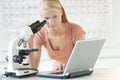 Student Looking At Laptop While Using Microscope Royalty Free Stock Photo