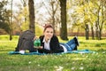 Student lying on a meadow holding a piggy bank Royalty Free Stock Photo