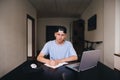 A student makes a homework job while sitting in his home. Teens study at home. A look at the camera.