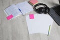 Student notebook with paper on desktop with pen and pencil. Laptop and headphones on table