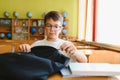 Student opening backpack at school desk getting ready for class Royalty Free Stock Photo