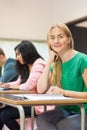 Student with others writing notes in classroom Royalty Free Stock Photo