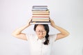 Young Asian woman holding a pile of books puffing cheeks with funny face. mouth inflated with air, catching air. Royalty Free Stock Photo