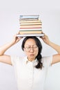 Young Asian woman holding a pile of books puffing cheeks with funny face. mouth inflated with air, catching air. Royalty Free Stock Photo