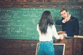 Student and professor having discussion in classroom. Rear view girl in blue jeans and white jumper standing in front of Royalty Free Stock Photo