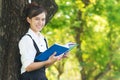Student reading book in park, standing under a tree. Relaxing outdoors reading. Royalty Free Stock Photo