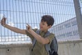 A Student resting outside a school and playing with a mobile phone