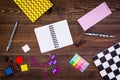 Student`s desk. Notebook, bright stationery on dark wooden background top view