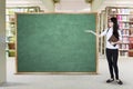 Student shows empty chalkboard in library Royalty Free Stock Photo