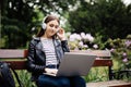 Time for little rest. Student sitting on bench listening to music and using laptop and wearing headphones in University campus par Royalty Free Stock Photo
