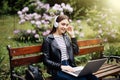 Time for little rest. Student sitting on bench listening to music and using laptop and wearing headphones in University campus par Royalty Free Stock Photo
