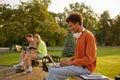 Student sitting on bench in university park and studying on laptop Royalty Free Stock Photo
