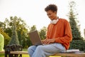 Student sitting on bench in university park and studying on laptop Royalty Free Stock Photo