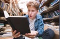 A student sitting on the floor in a public library and enthusiastically interested in reading a book Royalty Free Stock Photo