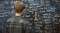 Student solves math problem at blackboard, boy teenager thinks and looks at formulas in class, back view. Concept of child, kid,