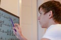A student solves math problems on a computer. a teenage boy is studying online