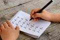 Student solves multiplication examples. Child holds a black marker in his hand and writes answers Royalty Free Stock Photo