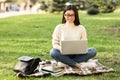 Student in specs using laptop, sitting in the park Royalty Free Stock Photo