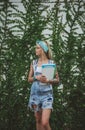 The student is standing by the wall with green plants waiting for classes in biology. Modern girl. Model of tattoos