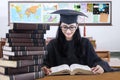 Student studying in the class while wearing mortarboard