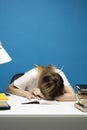 Student studying exam and sleeping on books on a blue background. Tired student girl with glasses sleeping on the books Royalty Free Stock Photo