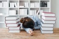 Student studying hard exam and sleeping on books, tired girl read difficult book in library Royalty Free Stock Photo