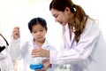 Student and teacher in lab coat have fun together while learn science experiment in laboratory. Young adorable Asian scientist kid