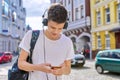 Student teenager in headphones with backpack looks into the smartphone screen Royalty Free Stock Photo